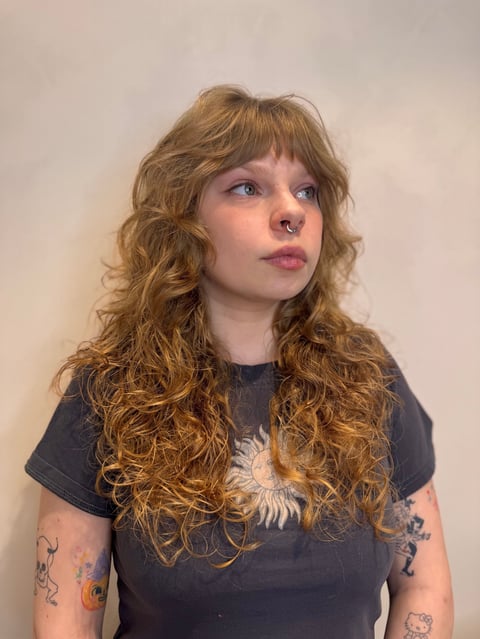Woman with long curly reddish-brown hair and bangs